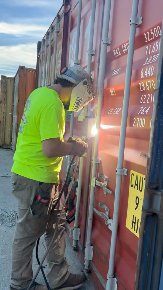 Welder working on-site on a row of shipping containers